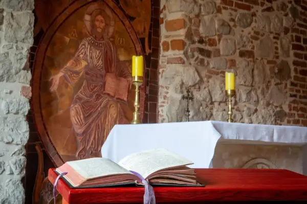Ołtarz z otwartą księgą, świecami i mozaiką Chrystusa. Ilustruje etapy rozwoju wiary według psychologii rozwojowej.