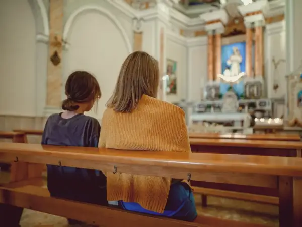 Dwie osoby siedzą w kościele. Zastanawiają się, jakie są obowiązki świadka bierzmowania i kto może nim zostać.