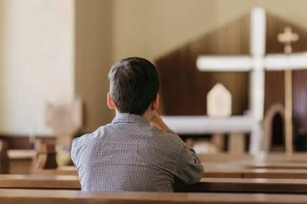 Chłopiec w kościele, zastanawiający się nad przyczynami odejść młodych ludzi z kościoła i dylematami pokoleniowymi.