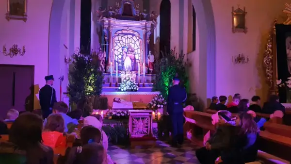 Wnętrze bazyliki Grobu Pańskiego, przygotowania do nocnej modlitwy. Wierni siedzą w ławkach, przy ołtarzu stoi wartownik.