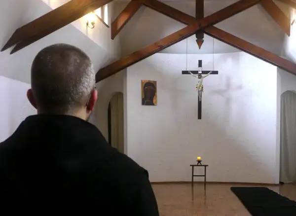 Mężczyzna w czerni rozważa jak odnaleźć swoje powołanie życiowe, znaki i dylematy wyboru, patrząc na krzyż.