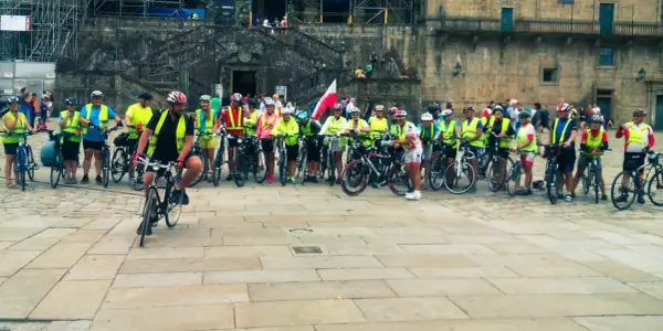 Grupa rowerzystów w kamizelkach odblaskowych przed katedrą. Szukasz najlepszych tras pielgrzymkowych w Polsce dla rowerzystów?