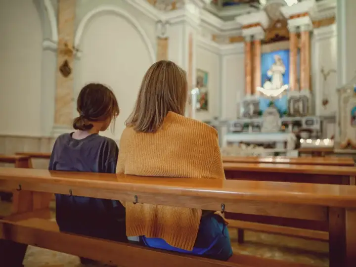 Dwie osoby siedzą w kościele. Zastanawiają się, jakie są obowiązki świadka bierzmowania i kto może nim zostać.